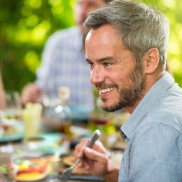 man smiling while eating with a group of people
