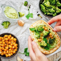 bowl of broccoli, bowl of chickpeas, hands making a pita with broccoli and chickpeas