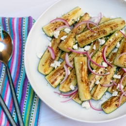 plate filled with greek zucchini slices with a colorful napkin and utensils