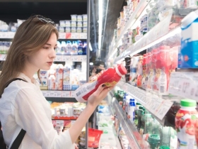A woman reading labels while shopping for dairy at grocery store