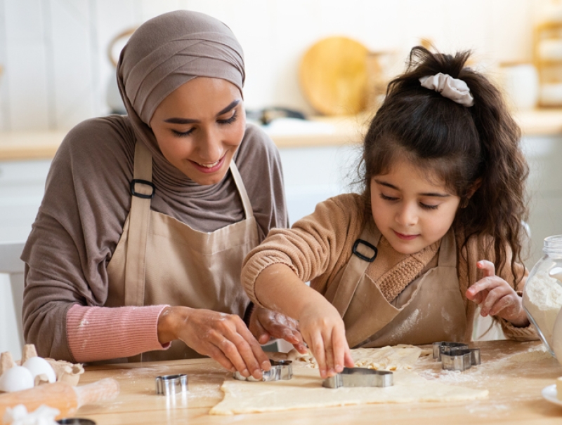Woman and young girl cutting cookie dough into shapes