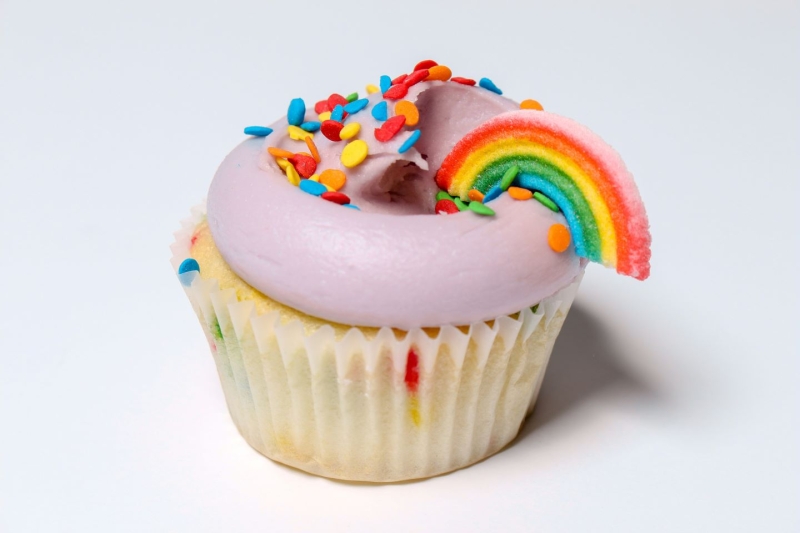 A funfetti cupcake with colorful rainbow decorations