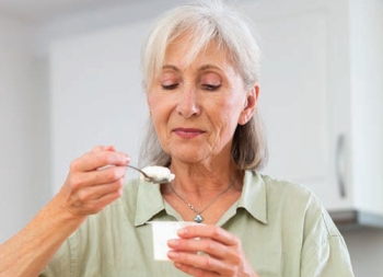 Older woman eating a cup of yogurt