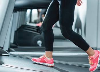 legs of a person walking on a treadmill at an incline