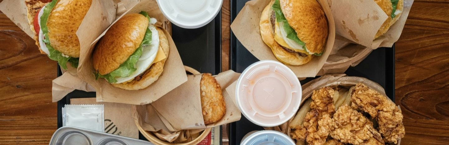 Flat lay of fast food burgers and fried foods with soda