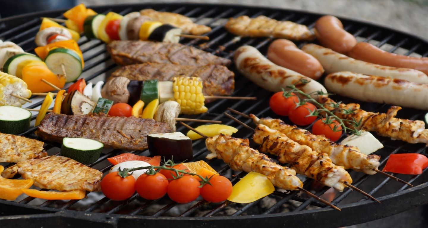 Sausages and vegetable kebabs on a grill