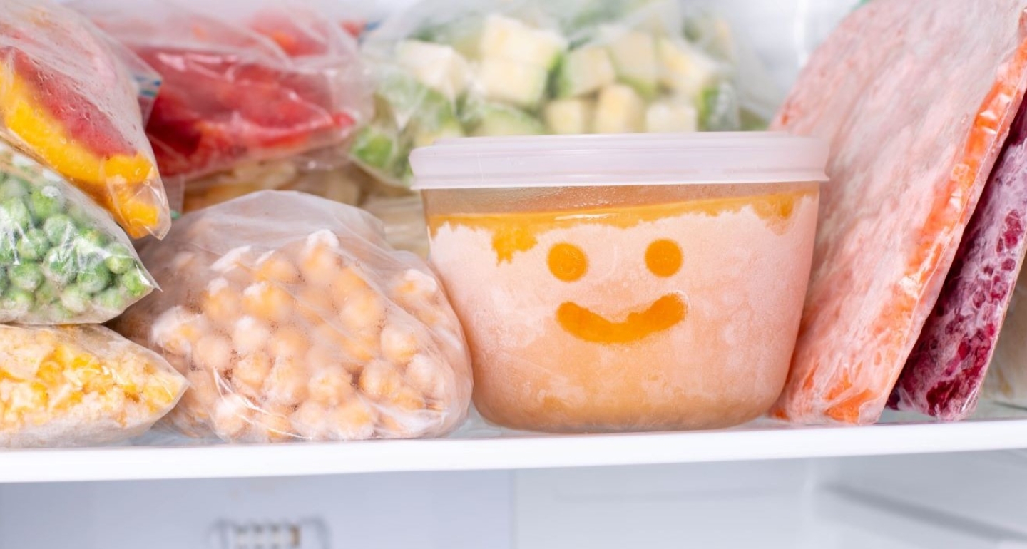 Frozen vegetables in a freezer. A bowl of frozen food with a smiley face drawn in the frost