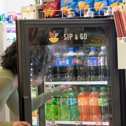 woman reaching into a soda cooler at checkout