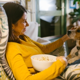 a woman eating popcorn while petting her dog