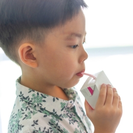 young child sipping from a juice box with straw