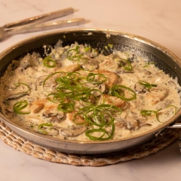 large pan filled with chicken, mushrooms, creamy sauce and topped with green scallion strips