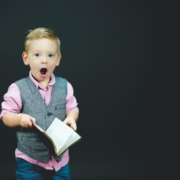 A young boy surprised by the contents of a book he's reading