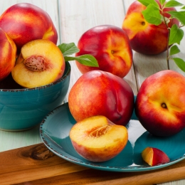 a blue bowl filled with nectarines next to a blue plate of nectarines