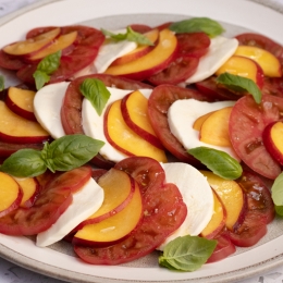 Plate with tomato, mozzarella, nectarine slices and basil