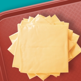 A stack of cheese slices on a cafeteria tray.