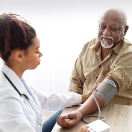 doctor checking blood pressure of older man
