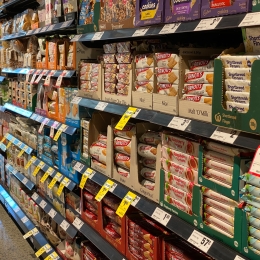 A supermarket shelf filled with pre-packaged products that lack front of package labeling