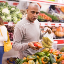 man picking out produce in a grocery store