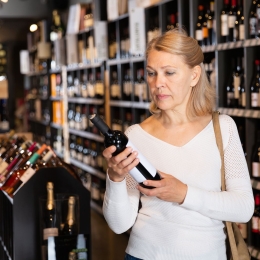 A woman checking the label on a bottle of wine