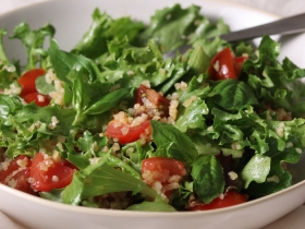 sliced tomato and cooked bulgur over leaf lettuce