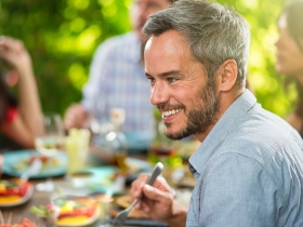 man smiling while eating with a group of people