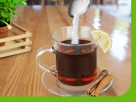 clear mug holding tea pouring sugar into