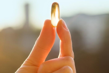 a hand holding a vitamin d pill
