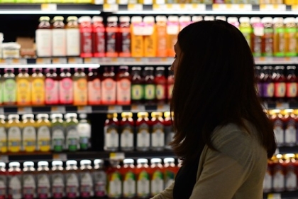 Woman browses beverages in grocery store aisle