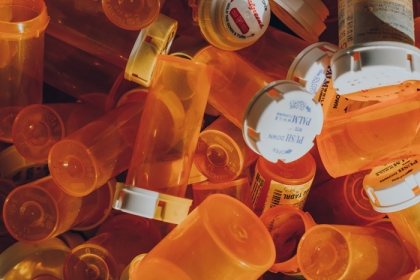 Several orange prescription bottles on top of each other 