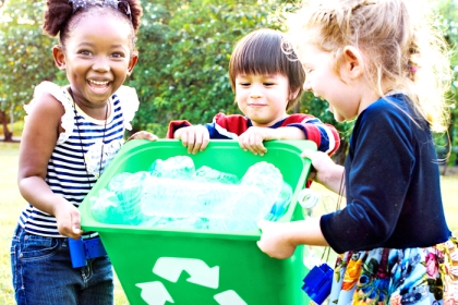 3 children carrying green recycle bin