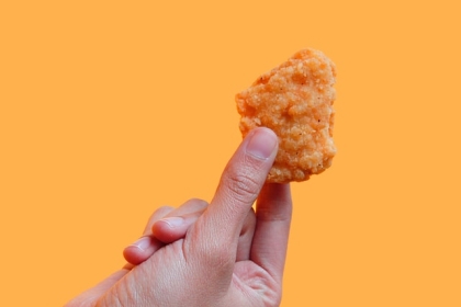 A hand holding a chicken nugget