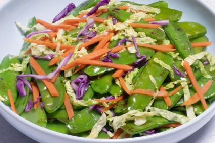 Plate with stir-fried snow peas, shredded carrots and cabbage
