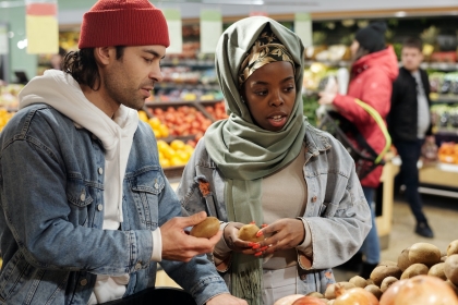 A young man and woman shopping in a grocery store produce aisle