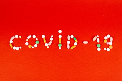 Various pills and capsules arranged to spell "Covid-19"
