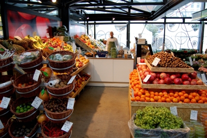 A view of a grocery store showing a checkout counter framed by baskets of produce