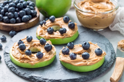 Plate with green apple slices covered in peanut butter and sprinkled with blueberries