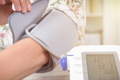 person fastening a blood pressure monitor on their arm