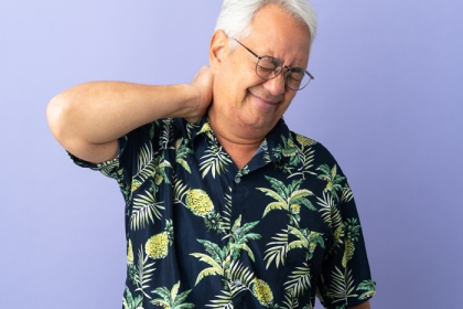 Older man holding the back of his neck and wincing