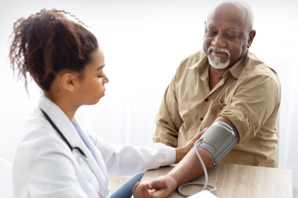 doctor checking blood pressure of older man