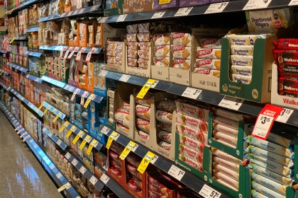 A supermarket shelf filled with pre-packaged products that lack front of package labeling