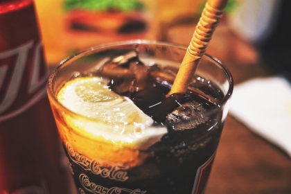 A glass of cola with ice and an orange wedge