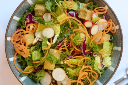 bowl of salad with greens and sliced vegetables