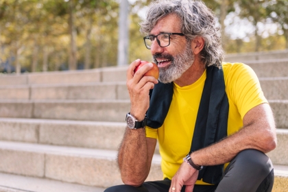 man sitting on steps outside eating an apple