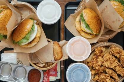 Flat lay of fast food burgers and fried foods with soda