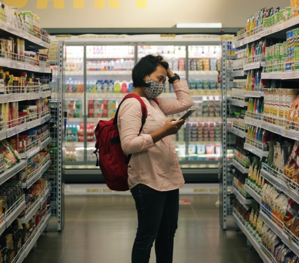 A woman in a grocery store peruses the snack aisle