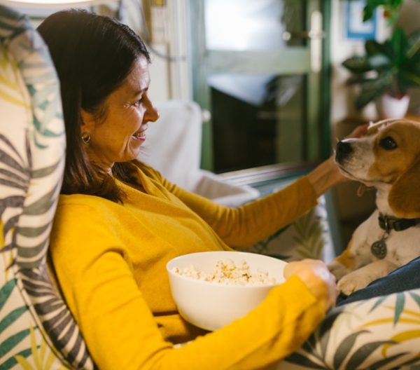 a woman eating popcorn while petting her dog
