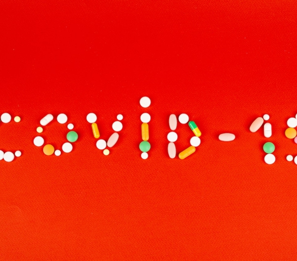 Various pills and capsules arranged to spell "Covid-19"