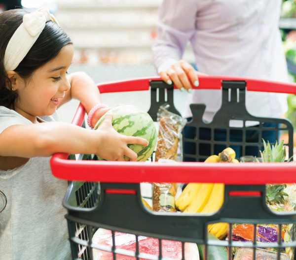 Young girl placing produce into a shopping cart