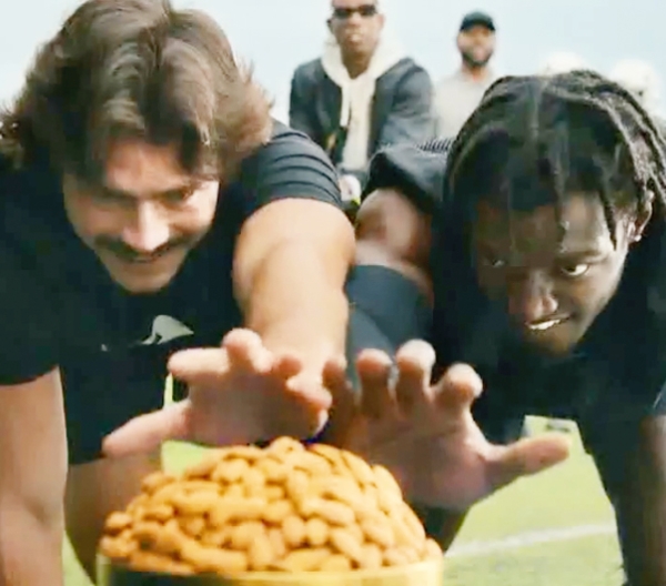 2 men reaching towards a pile of almonds in the foreground