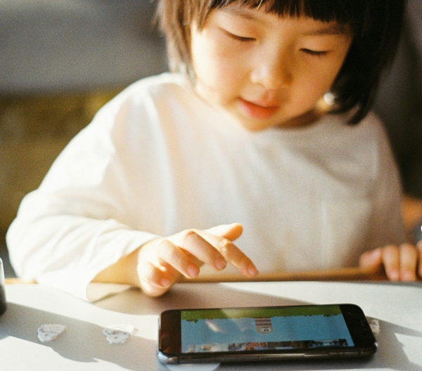 A young child watches cartoons on a small tablet